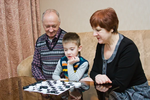 En mormor, grand-pappa, spela med ett barnbarn i brickor — Stockfoto