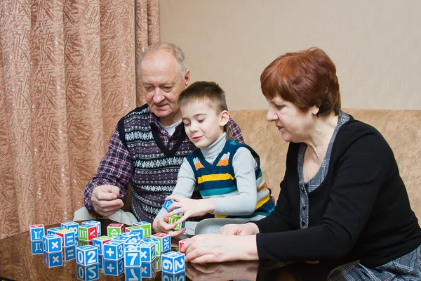 Een grootmoeder en de grand-papa spelen met een kleinkind in blokken — Stockfoto