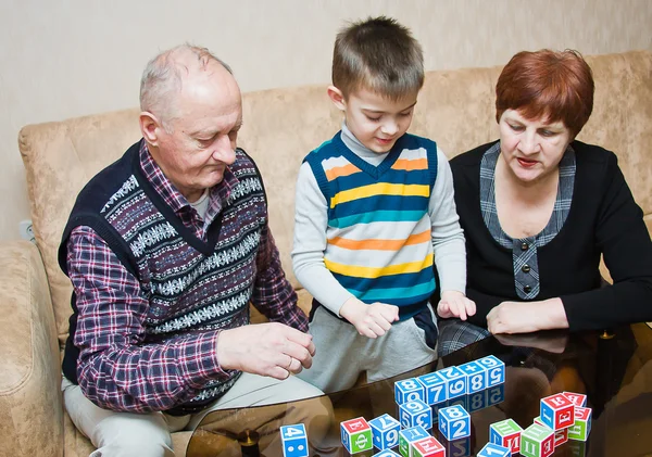 Een grootmoeder en de grand-papa spelen met een kleinkind in blokken — Stockfoto