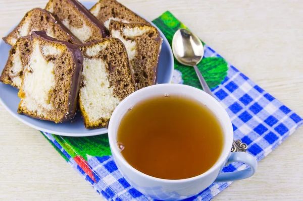 Tasse mit heißem Tee und süßen Kuchen auf dekorativer Serviette — Stockfoto