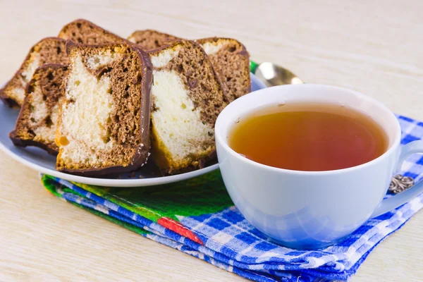 Tasse mit heißem Tee und süßen Kuchen auf dekorativer Serviette — Stockfoto