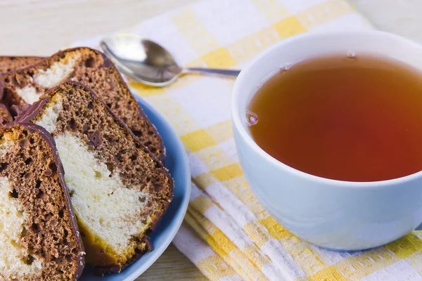 Tasse mit heißem Tee und süßen Kuchen auf dekorativer Serviette — Stockfoto
