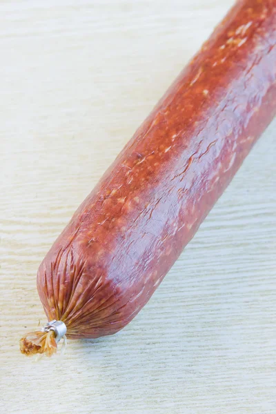 Pão longo a linguiça defumada em uma superfície de madeira — Fotografia de Stock