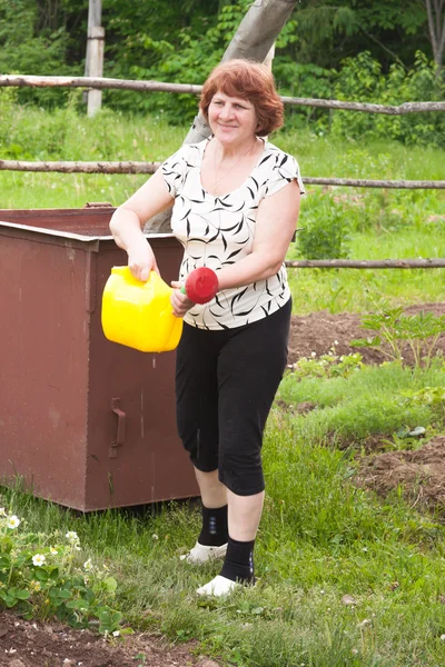 An elderly woman works in a garden — Stock Photo, Image