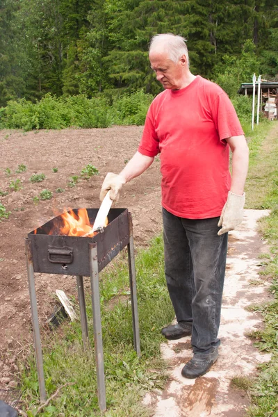 Un anciano cocina en la naturaleza —  Fotos de Stock