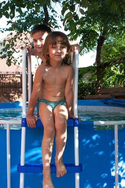 Uma menina alegre senta-se na escada da piscina — Fotografia de Stock