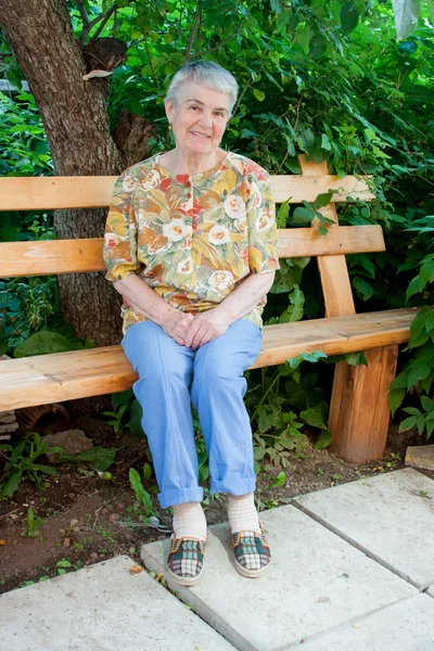 En äldre kvinna sitter på en bänk — Stockfoto