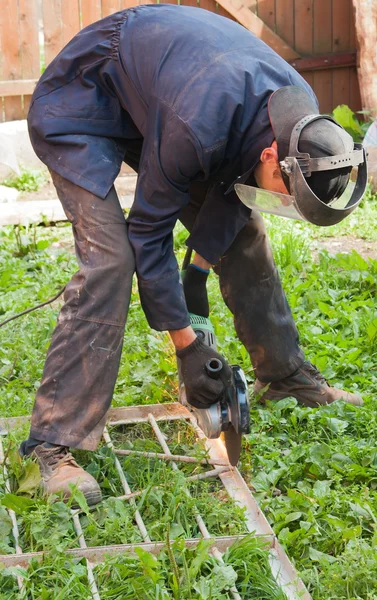 Man arbetar utanför, skär en metall — Stockfoto