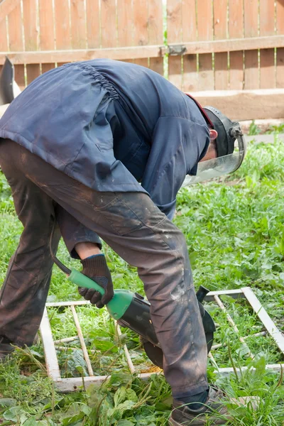 Mann arbeitet draußen, schneidet ein Metall — Stockfoto