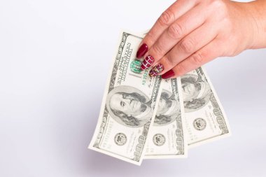 Manikürlü kadın elleri, kopyalama alanı olan beyaz bir arkaplanda dolar tutuyor..