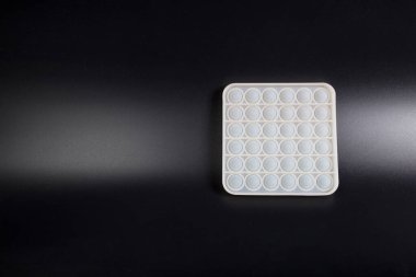 Siyah arkaplanda fotokopi alanı olan silikon kabarcık anti-stres oyuncağı.