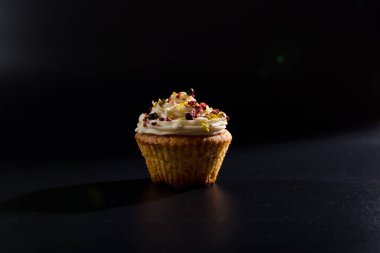 Siyah arka planda, üzerinde krema olan güzel bir fincan kek..