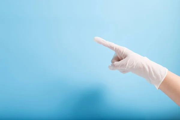 Doctoe Mão Luva Látex Branco Apontando Para Esquerda Fundo Azul — Fotografia de Stock