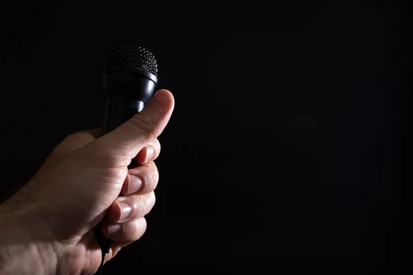 Männliche Hand Hält Schwarzes Karaoke Mikrofon Nahaufnahme Auf Schwarzem Hintergrund — Stockfoto
