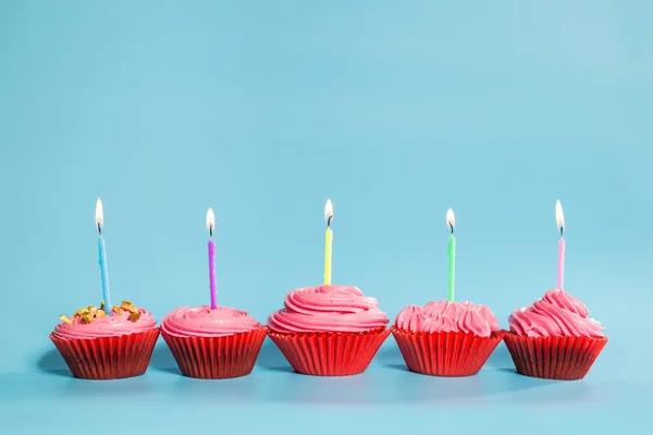 Geburtstag Cupcakes Mit Kerzen Auf Blauem Hintergrund Mit Kopierraum lizenzfreie Stockbilder