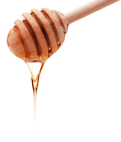 白い背中に分離された木製蜂蜜ディッパーから滴る蜂蜜 — ストック写真