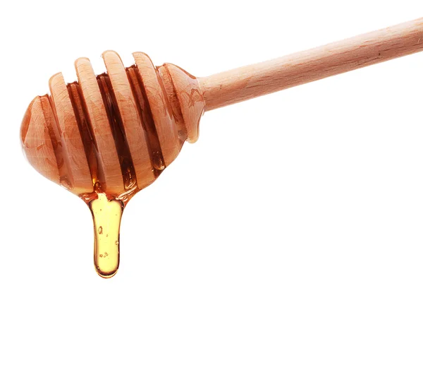 Honey dripping from a wooden honey dipper isolated on white back — Stock Photo, Image