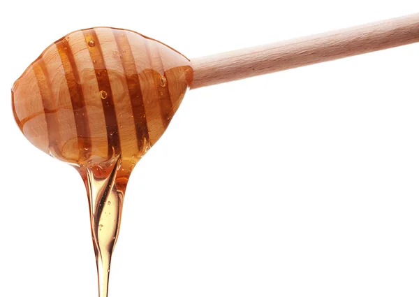 Honey dripping from a wooden honey dipper isolated on white back — Stock Photo, Image