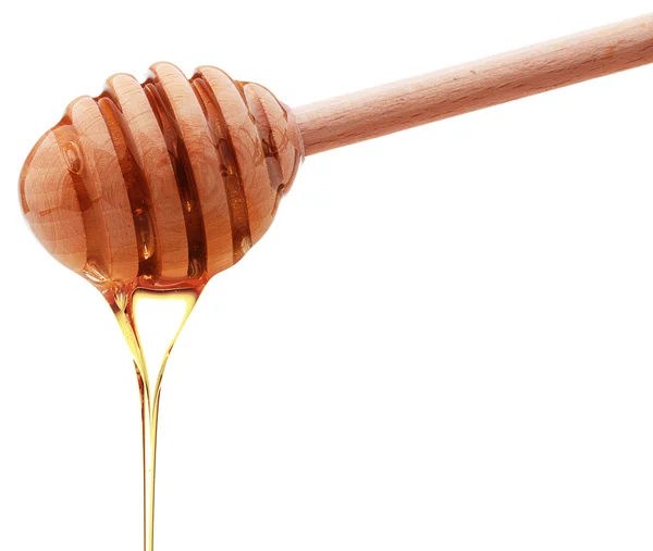 Honey dripping from a wood honey dipper isolated on white back — Stok Foto