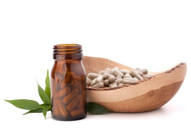 Herbal drug capsules in brown glass bottle.