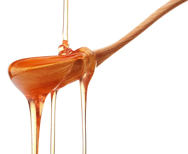 Honey dripping from a wooden honey dipper isolated on white back — Stock Photo, Image