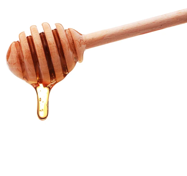 Honey dripping from a wooden honey dipper isolated on white back — Stock Photo, Image