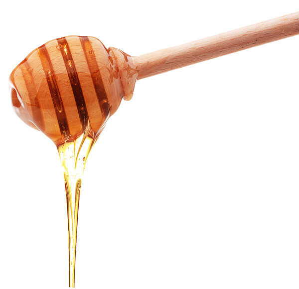 Honey dripping from a wooden honey dipper isolated on white back