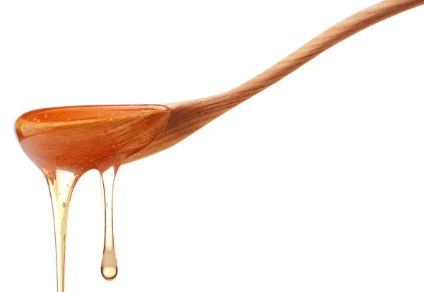 Honey dripping from a wooden honey dipper — Stock Photo, Image