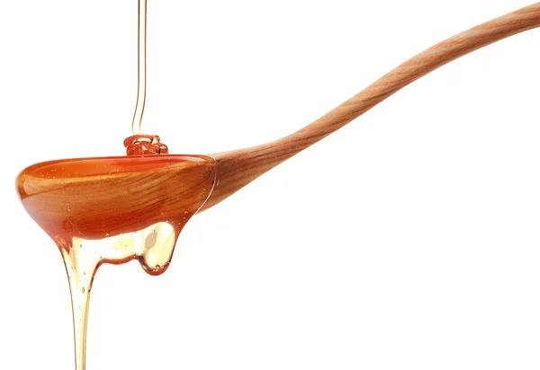 Honey dripping from a wooden honey dipper isolated on white back — Stock Photo, Image