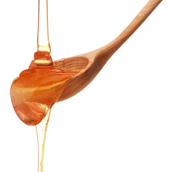 Honey dripping from a wooden honey dipper — Stock Photo, Image