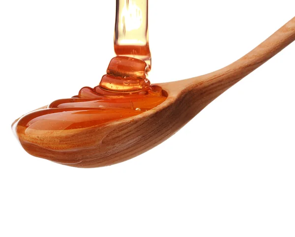 Honey dripping from a wooden honey dipper — Stock Photo, Image