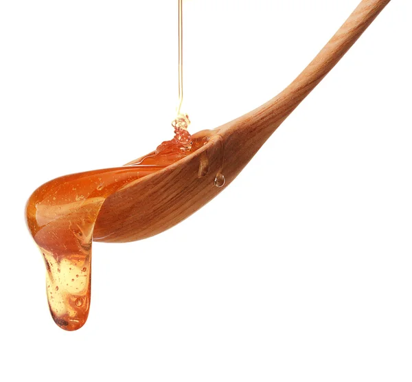 Honey dripping from a wooden honey dipper — Stock Photo, Image