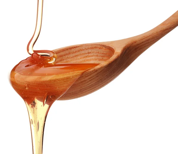 Honey dripping from a wooden honey dipper — Stock Photo, Image