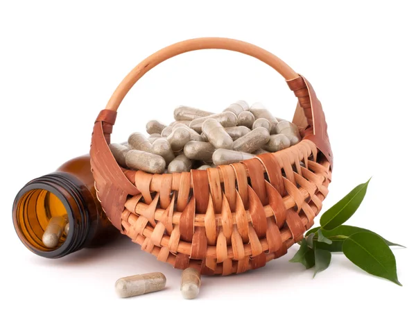 Herbal drug capsules in wicker basket — Stock Photo, Image