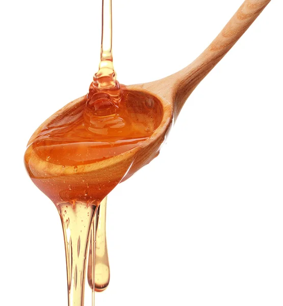 Honey dripping from a wooden honey dipper — Stock Photo, Image