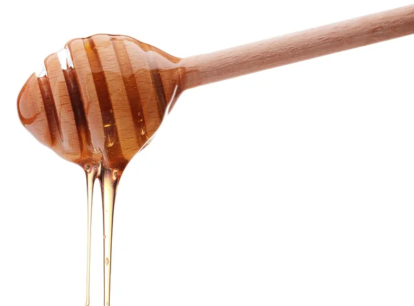 Honey dripping from a wooden honey dipper isolated on white back — Stock Photo, Image