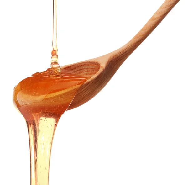 Miel goteando de un tarro de miel de madera aislado en la espalda blanca — Foto de Stock