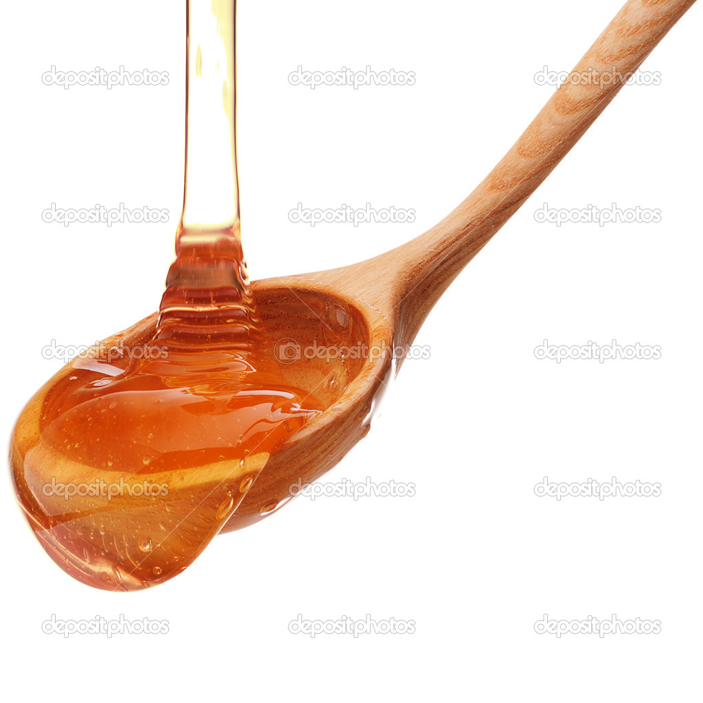 Honey dripping from a wooden honey dipper isolated