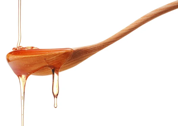 Honey dripping from a wooden spoon — Stock Photo, Image