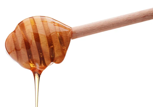 Honey dripping from a wooden honey dipper — Stock Photo, Image