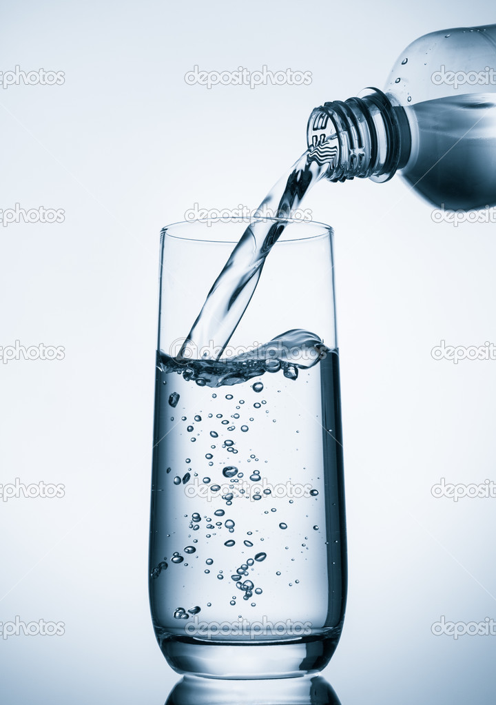 Pouring water into glass  from bottle on blue background 
