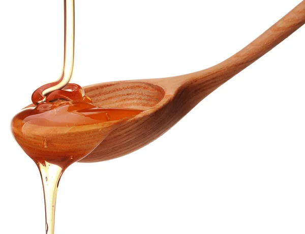 Honey dripping from a wooden honey dipper — Stock Photo, Image