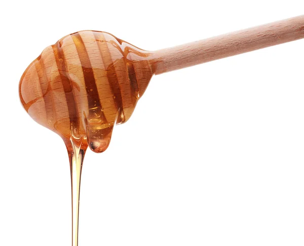 Honey dripping from a wooden honey dipper — Stock Photo, Image