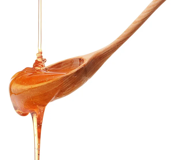 Honey dripping from a wooden honey dipper — Stock Photo, Image