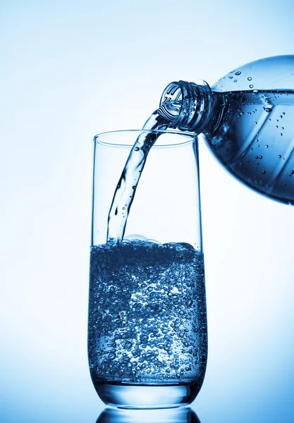 Hälla vatten i glas från flaskan — Stockfoto