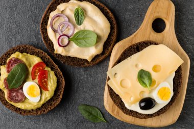 Açık yüzlü sandviç kanepe veya crostini taş koyu arka plan üzerinde bir ahşap hizmet gemide. Üstten görünüm.