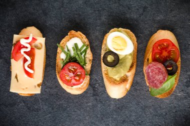 Açık yüzlü sandviç kanepe veya crostini taş koyu arka plan üzerinde. Üstten görünüm.