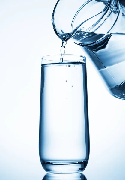 Gießen Von Wasser Aus Glaskannen Auf Blauem Hintergrund — Stockfoto