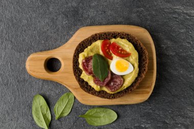 Açık yüzlü sosis sandviç kanepe veya crostini taş koyu arka plan üzerinde bir ahşap hizmet gemide. Üstten görünüm.