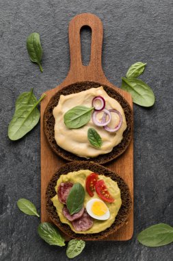 Açık yüzlü sosis sandviç kanepe veya crostini taş koyu arka plan üzerinde bir ahşap hizmet gemide. Üstten görünüm.
